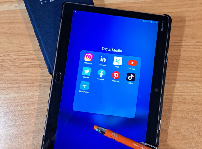 Buchkalender 2023, Kugelschreiber mit der Aufschrift HZ WebDesign, Tablet auf dem verschiedene Social Media Apps zusehen sind.