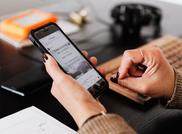 Eine Frau schaut sich auf ihrem Smarthphone verschiedene Social Media Kanäle an.