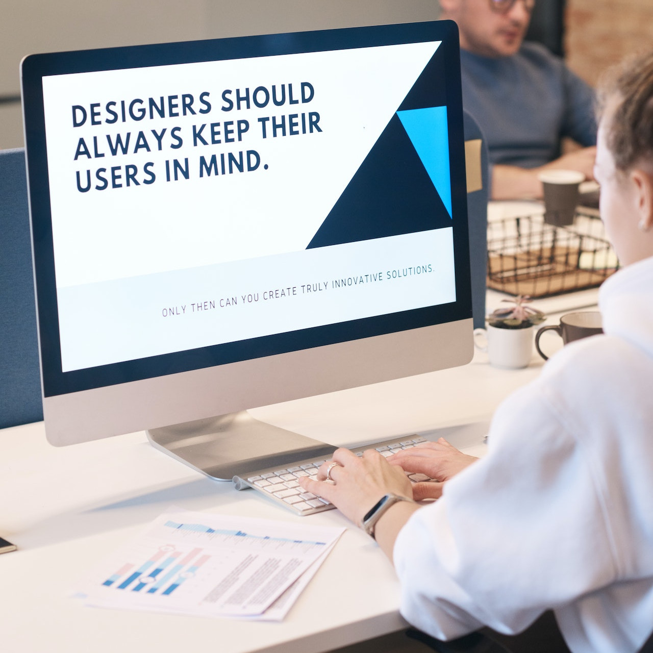 UX Designerin vor einem Monitor mit der Aufschrift "Designers schould always keep their users in mind.".